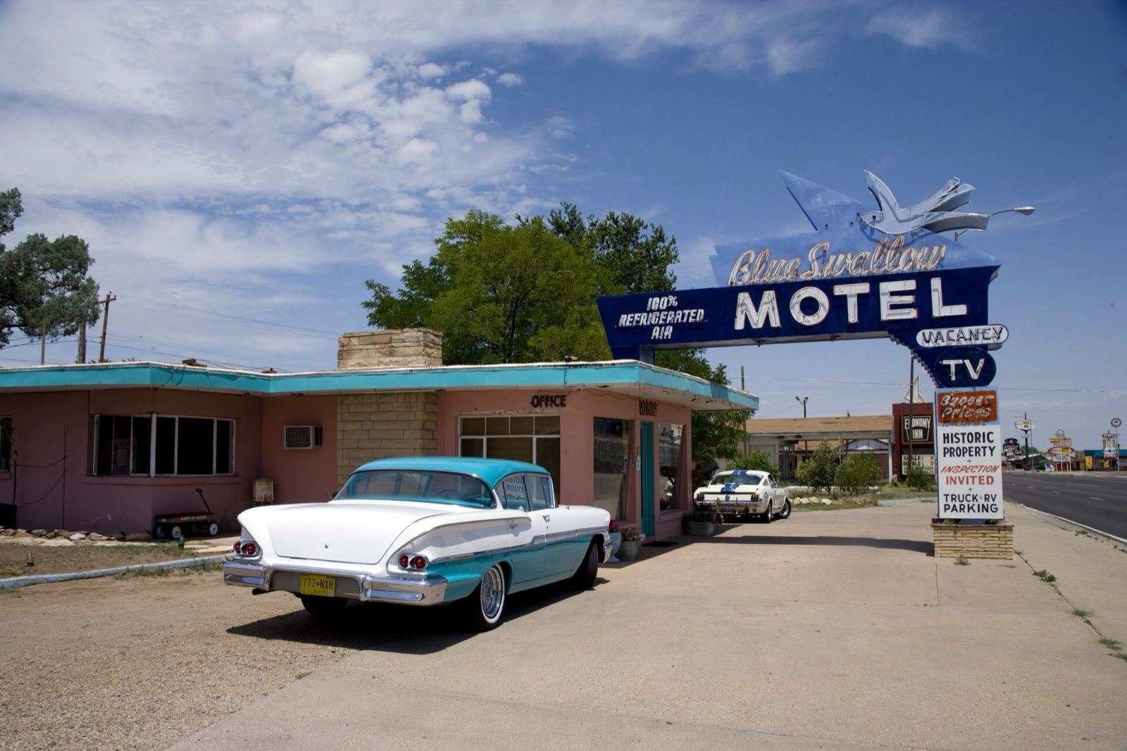 Blue Swallow Motel neon sign and pink office with a vintage sedan parked in front, Tucumcari, New Mexico